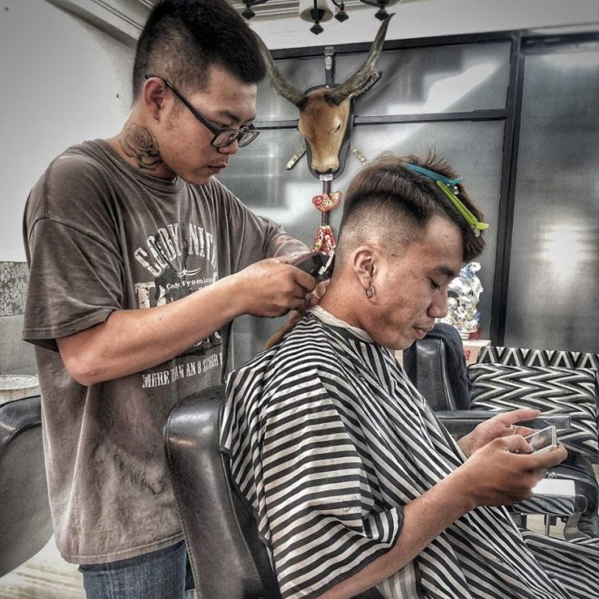 Một anh trai đang cắt tóc cho một anh trai khác