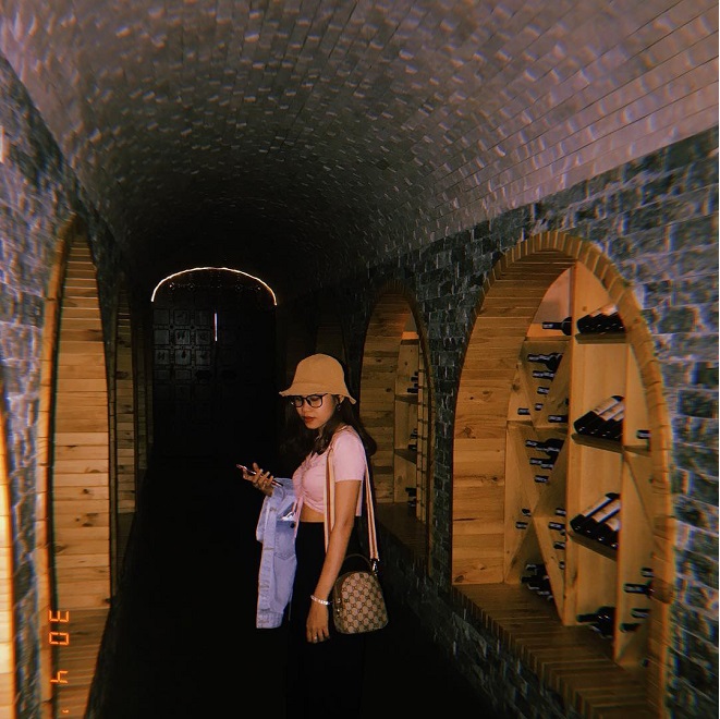 cô gái mặc áo hồng đứng trong tầng hầm của lâu đài rượu