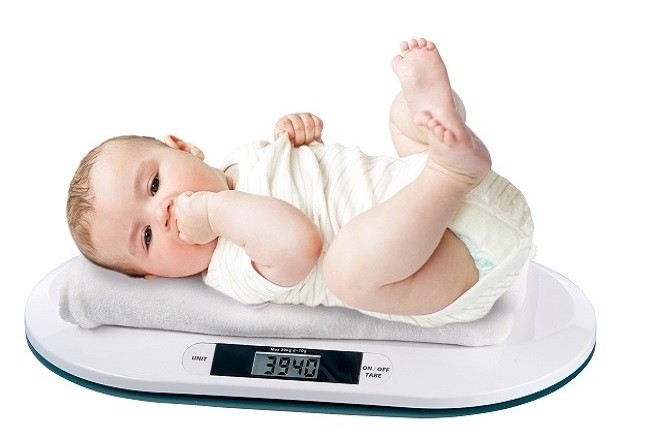 Bé 9 tháng tuổi nằm thăng bằng để đo cân nặng chính xác