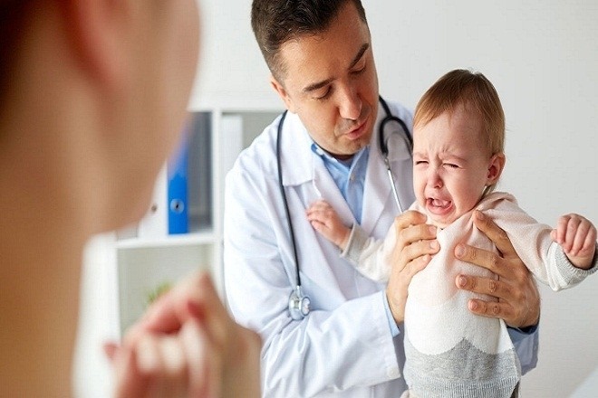 Bác sĩ đang ôm một đứa trẻ khóc