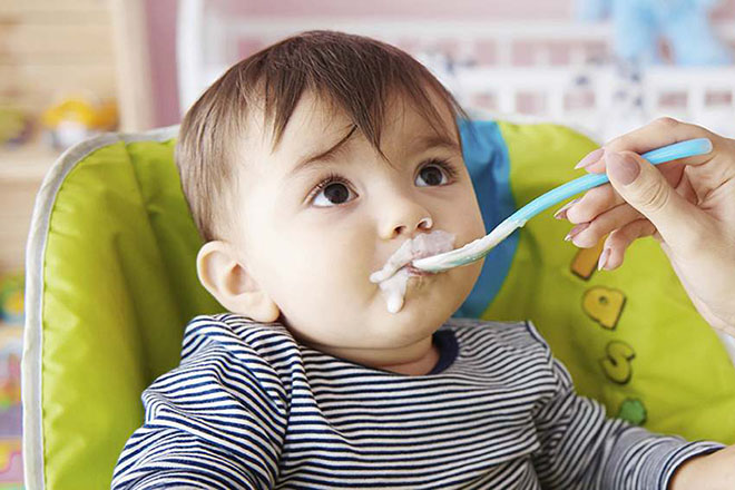 Một bà mẹ cho trẻ 7 tháng tuổi ăn sữa chua.