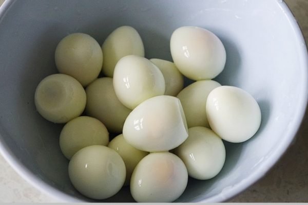 Trứng cút luộc chín, bóc vỏ và rửa sạch.