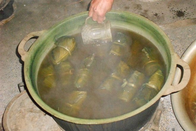 Đổ đầy nước vào nồi để luộc Bản Chung bằng bếp than.
