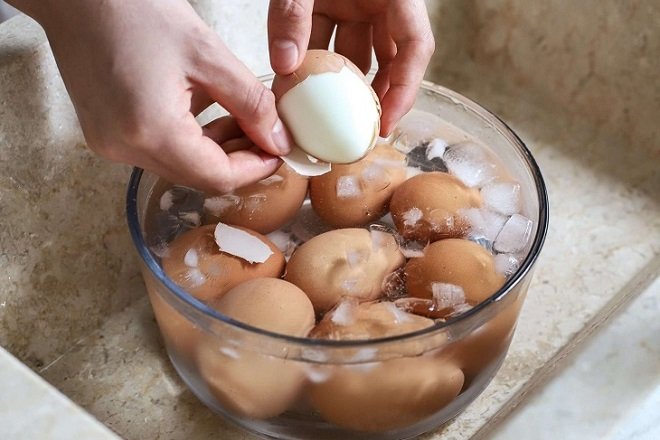 ngâm trứng luộc vào thau nước đá và bóc vỏ