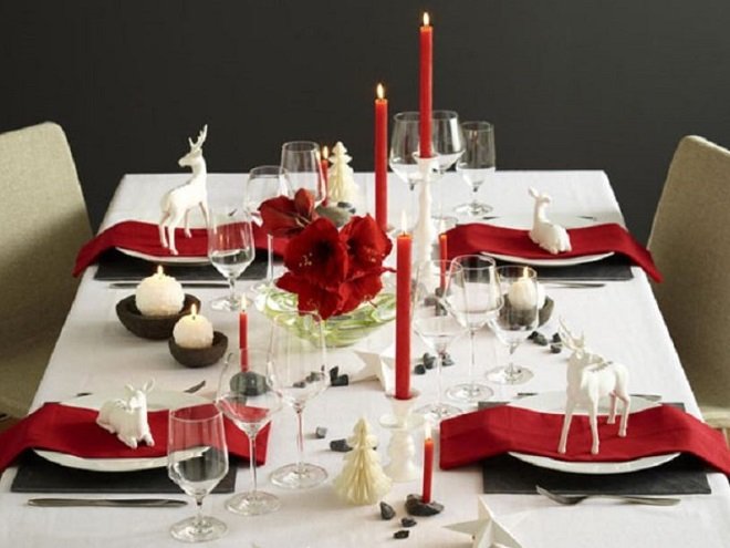 bày bàn tiệc giáng sinh với nến hoa đỏ và khăn ăn trắng
