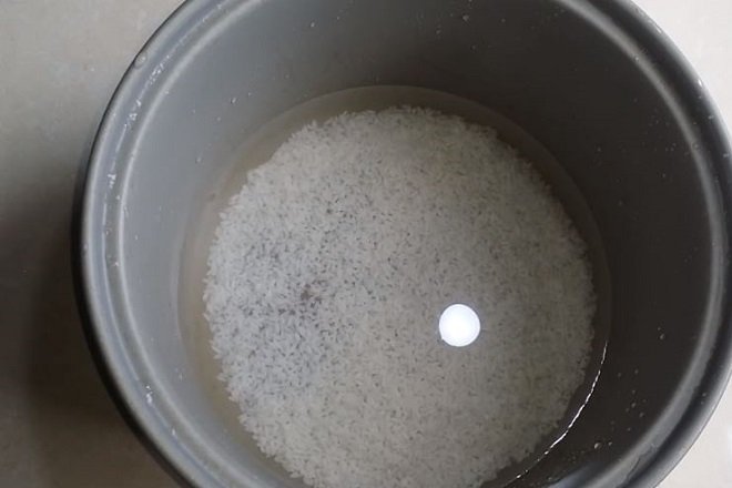 Cho nước và gạo vào nồi cơm điện để nấu cháo trắng.